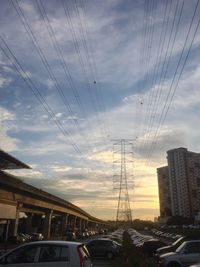 Cars on road amidst buildings against sky during sunset