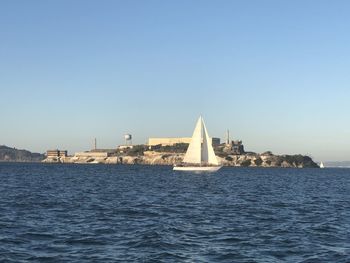 Sea by buildings against clear sky
