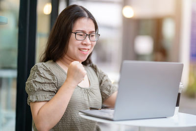 Portrait of young woman using laptop at table