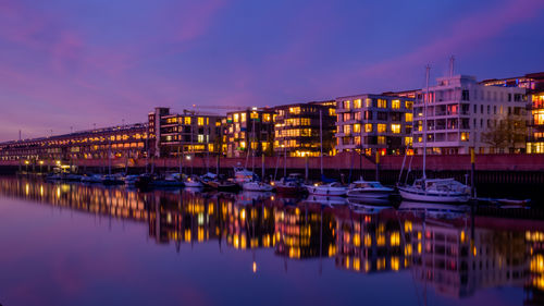 Sailboats moored on river against sky at dusk