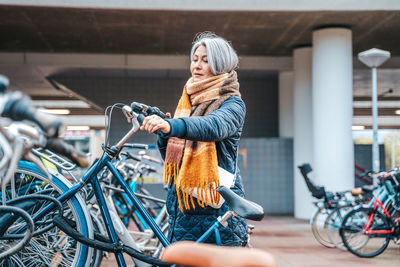 Mature woman with bicycle at parking station