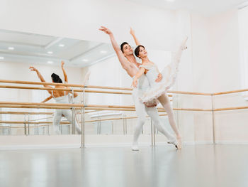 Full length of man and woman practicing ballet dance in studio