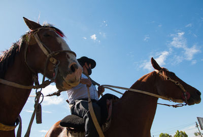 Low angle view of argentinian people riding horses