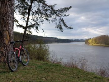 Bicycle by lake against sky