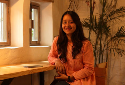 A girl smiling while sitting inside a cafe.