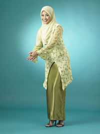 Portrait of woman in traditional clothing gesturing against green background