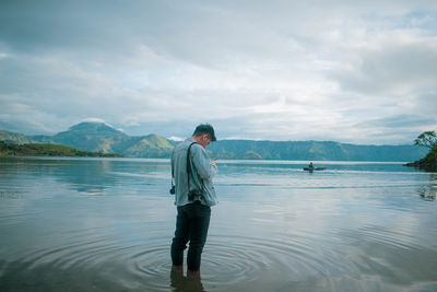 Full length of man standing in lake against sky