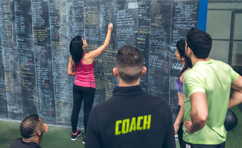 Rear view of woman writing on blackboard