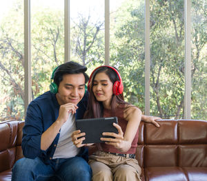 Young woman using phone while sitting on sofa