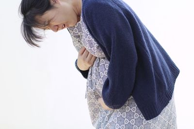 Side view of young woman standing against white background