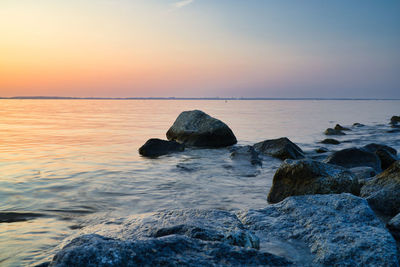 Rocks on sea against sky during sunset