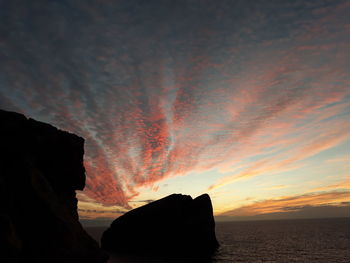 Rock formation on sea against sky during sunset