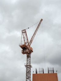 Low angle view of cranes at construction site against sky