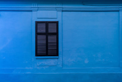 Low angle view of window on blue wall