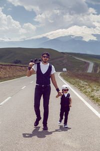 Father teaches son to ride a black skateboard on the road against the mount everest in the summer