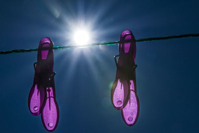 Low angle view of clothespins hanging on clothesline against sky