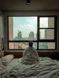 Rear view of woman sitting on bed