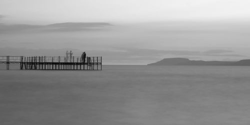 Double exposure of pier over lake against sky