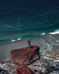 Man standing on rock by sea