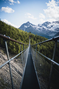 Footbridge over mountain against sky