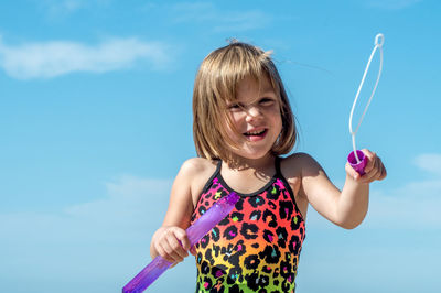 A happy child has fun with a tube of bubbles and a bubble wand