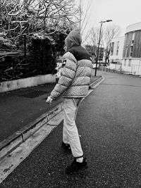 Rear view of child walking on snow covered road