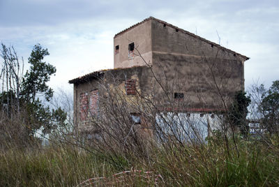 Old abandoned building on field against sky