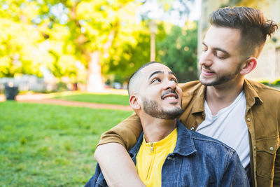 Gay couple standing at park while looking away