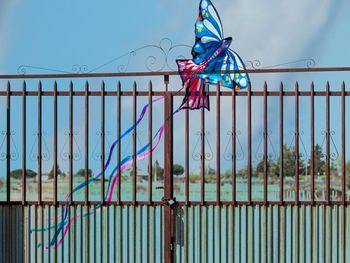 Kite on fence against blue sky