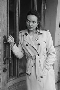 Portrait of woman standing against door