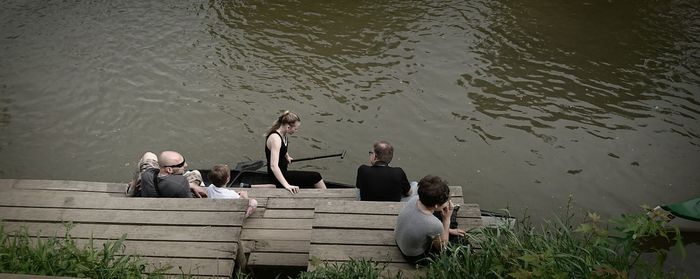 High angle view of people sitting by lake