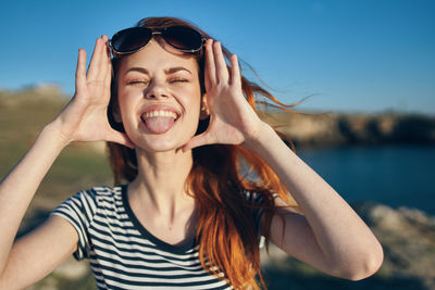 Portrait of beautiful young woman sticking out tongue outdoors