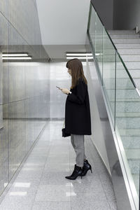 Side view of woman using phone in corridor