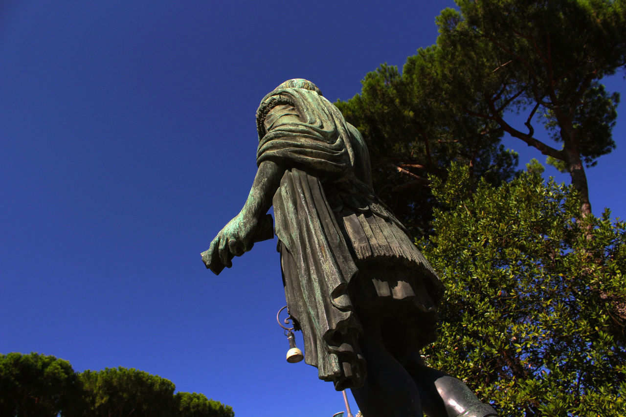 LOW ANGLE VIEW OF STATUE AGAINST TREES AGAINST CLEAR BLUE SKY