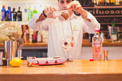 Portrait of bartender preparing drink at counter