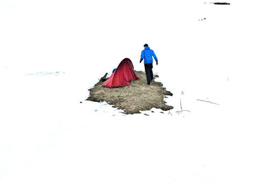 Rear view of people walking on snow covered field