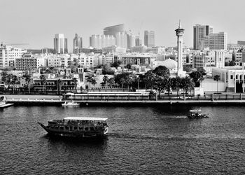 Boats in river against buildings in city