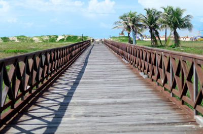 Surface level of wooden footbridge against sky