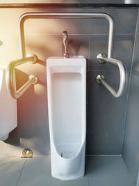 Urinal with handrails for disabled person in public restroom