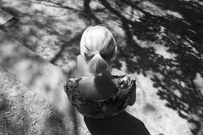 High angle view of woman reading book while sitting outdoors