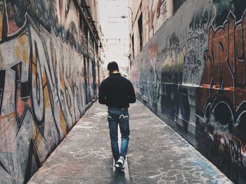 Rear view of man walking on walkway in city