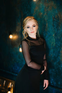 Portrait of young woman standing against wall