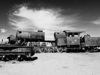 Abandoned train on field against sky