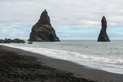 Rock formation on beach against sky