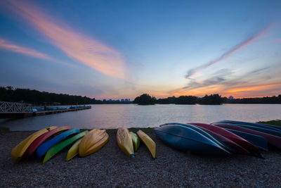 Boats moored on shore against sky during sunset