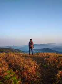 Rear view of man standing on mountain against sky