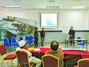 Rear view of people working on table