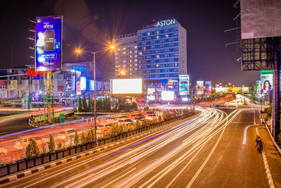 Light trails on city street by buildings at night