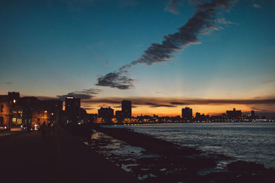 Illuminated city buildings against sky during sunset