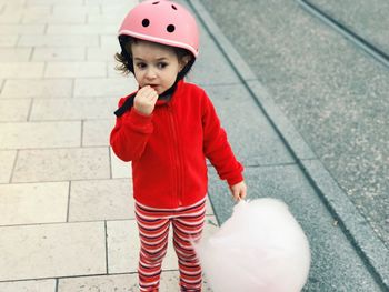 High angle view of boy holding cotton candy while standing on footpath
